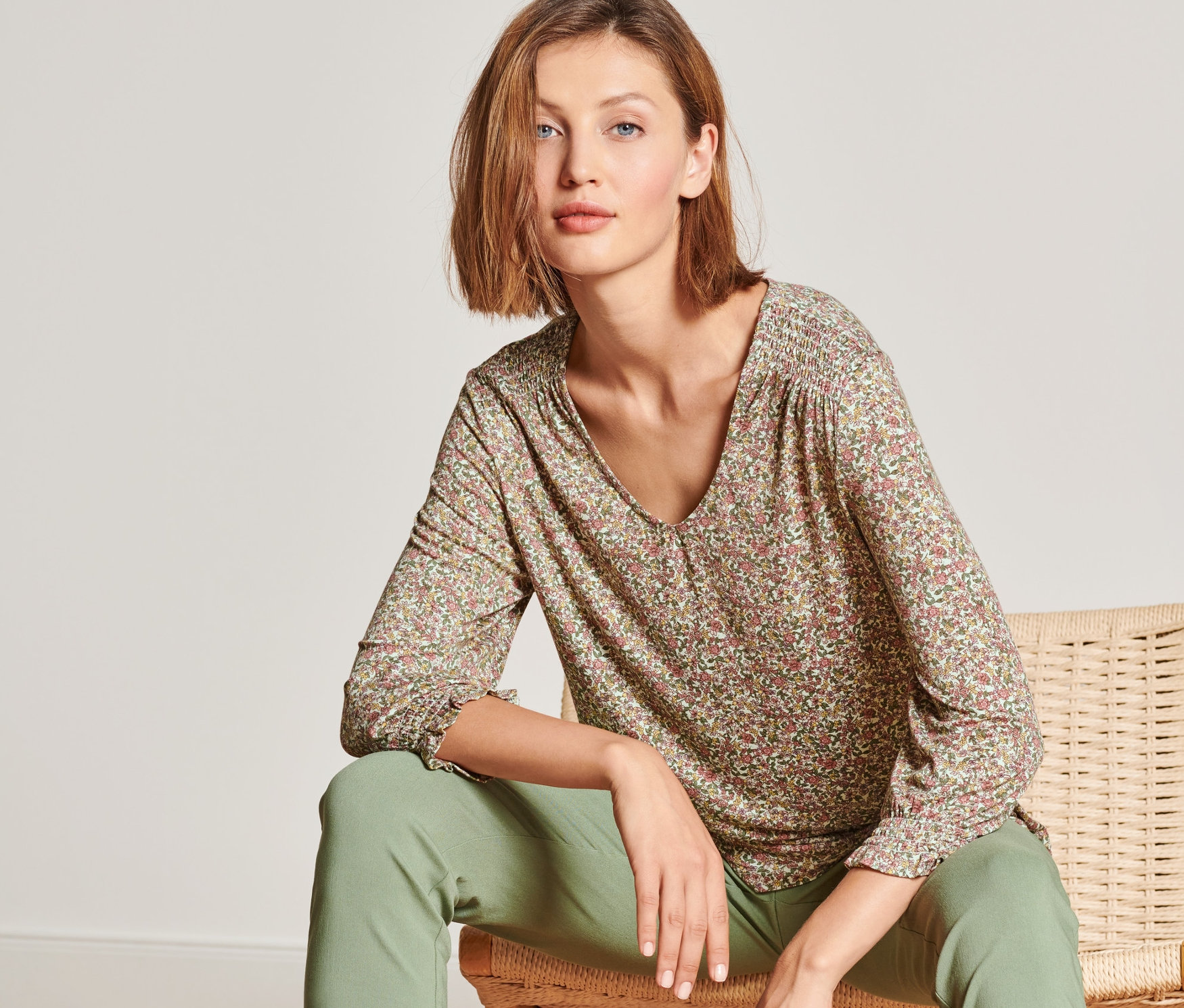 Femme assise sur une chaise portant une blouse manches 3/4.