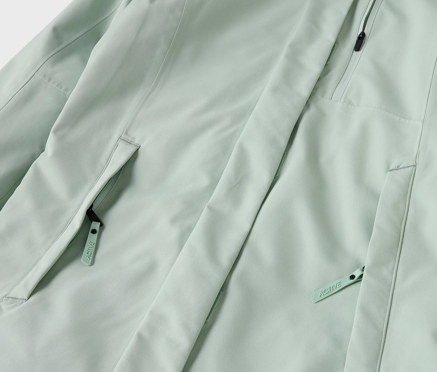 Détail d'une veste vert clair avec des poches zippées.