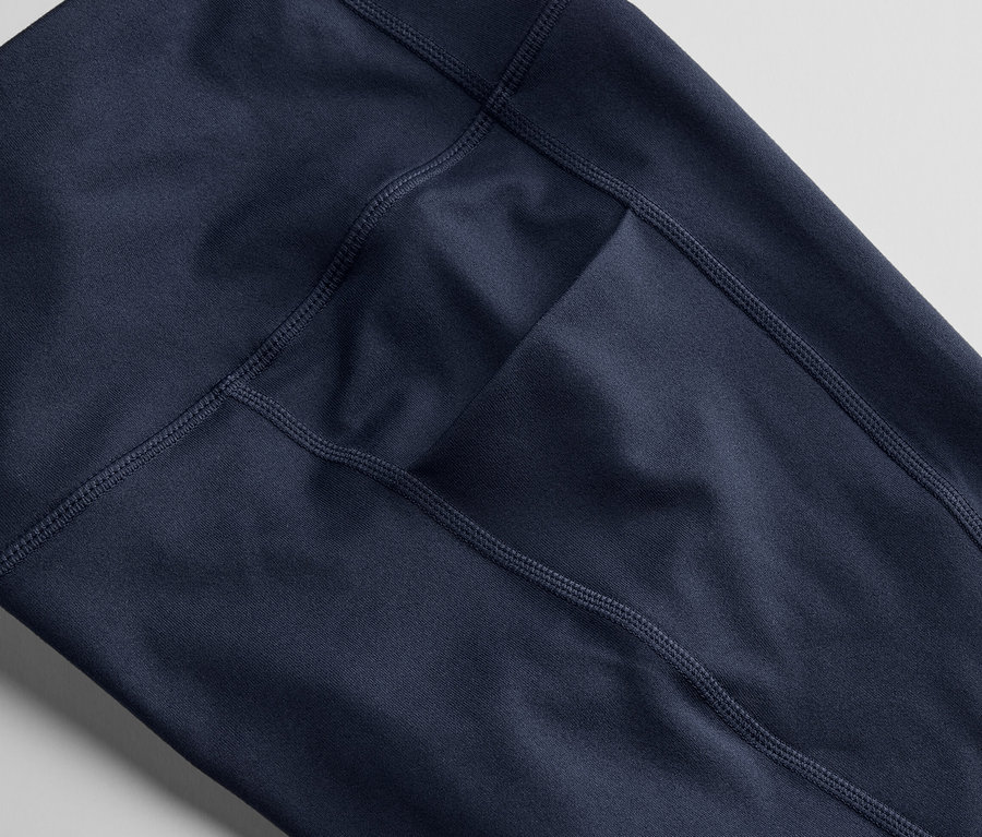 Gros plan sur un collant de sport 3/4 bleu foncé avec une poche.