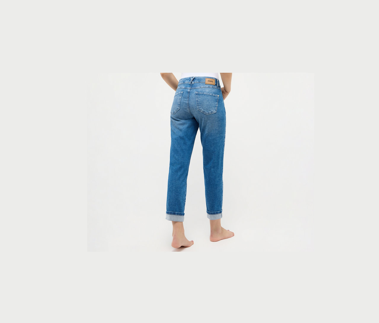 Une femme porte un jean Angels « Darleen » coupe cintrée 7/8, bleu clair.