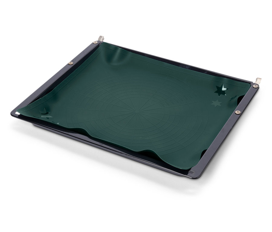 Plaque de cuisson noire avec un tapis en silicone vert foncé à motif circulaire.