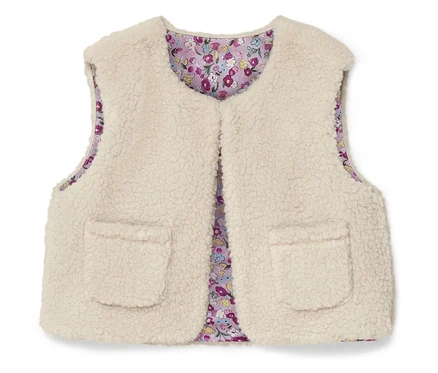 Un gilet sans manches crème et duveteux avec deux poches plaquées et une doublure à fleurs.