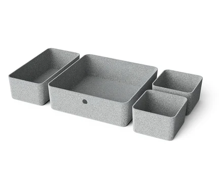 Quatre boîtes de rangement grises de différentes tailles disposées sur un fond blanc.