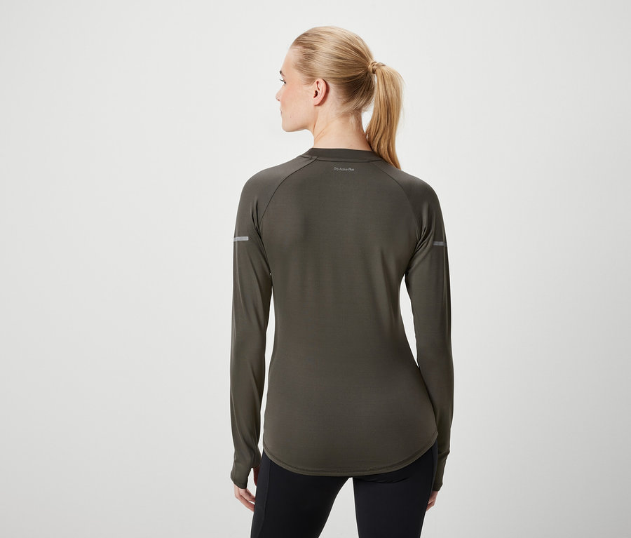 Vue de dos d'une femme aux cheveux blonds attachés en queue de cheval, portant un t-shirt à manches longues vert olive et un legging noir.