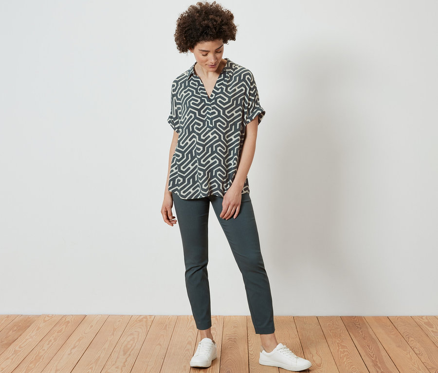 Femme debout portant une blouse imprimée.