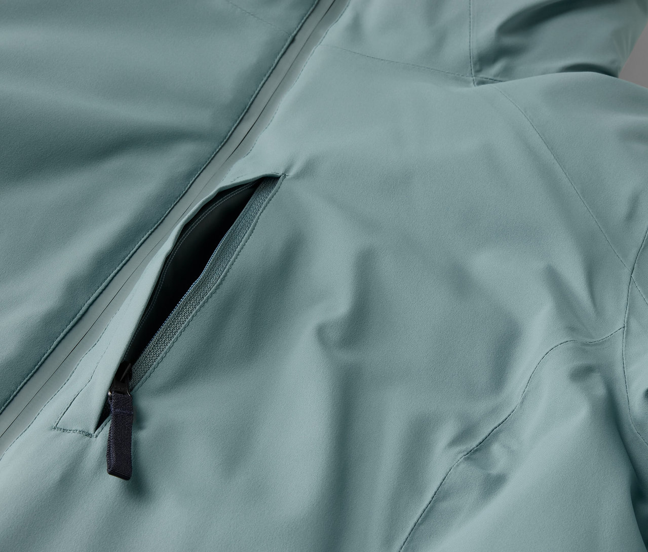 Détail d'une veste bleu clair avec une fermeture éclair noire.