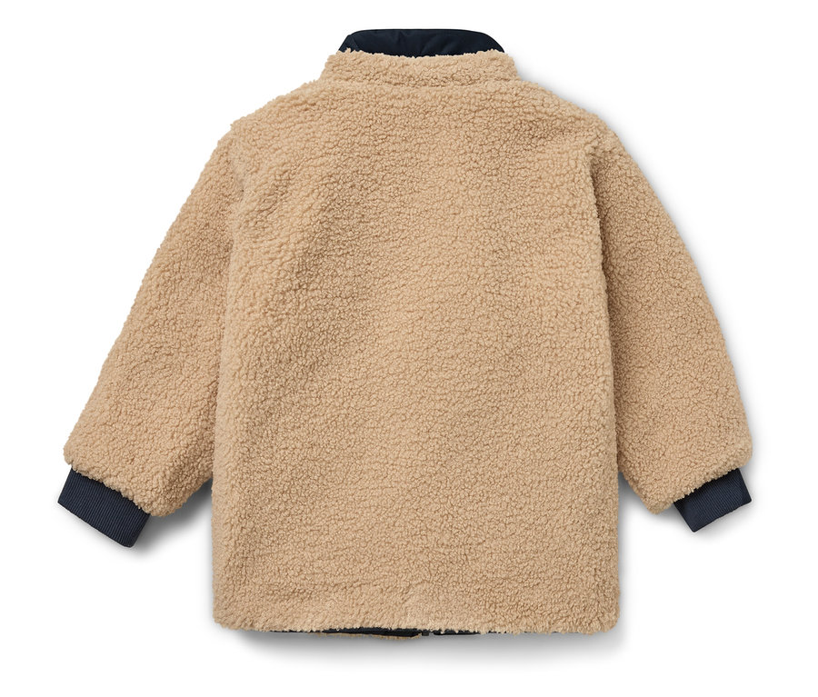 Une veste beige avec des poignets et un col bleu marine posée sur un fond blanc.