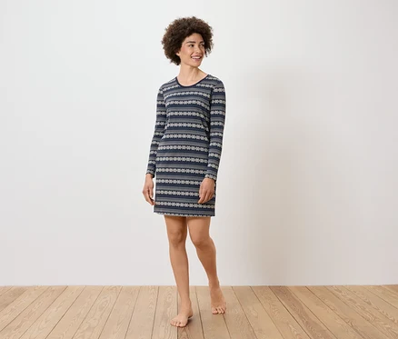 Une femme aux cheveux bouclés porte une robe bleue à manches longues avec un motif.