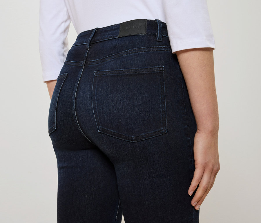 Vue arrière d'une femme portant un jean bleu foncé et un t-shirt blanc.