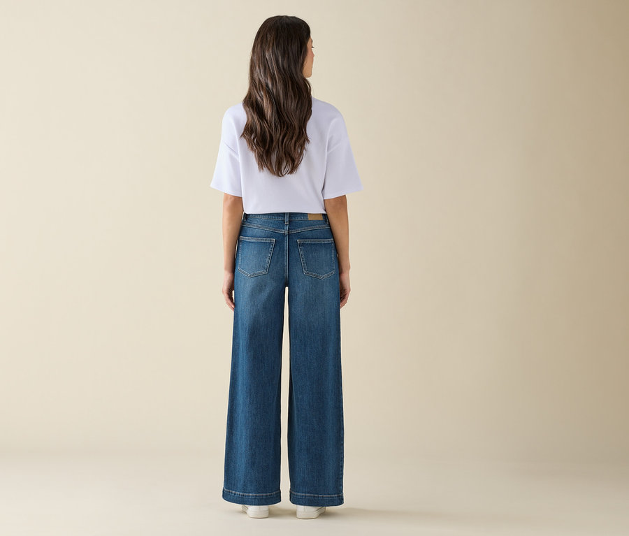 Une femme, vue de dos, porte un jean large et un t-shirt blanc.