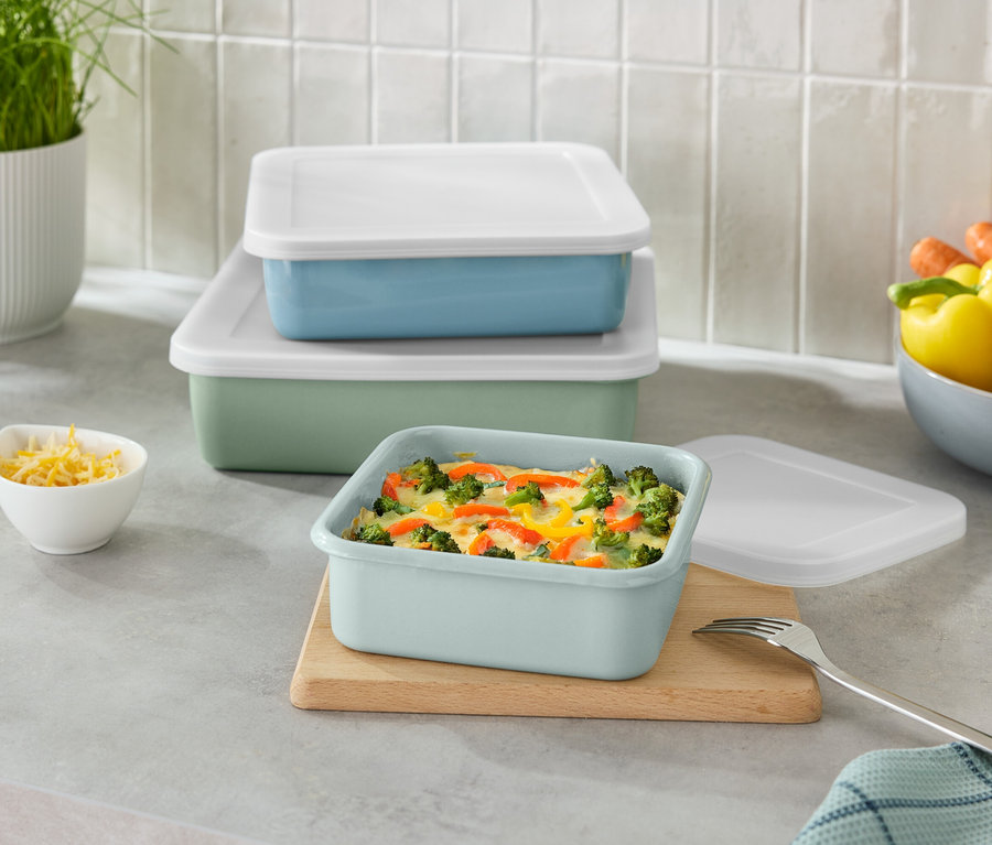 Récipients rectangulaires verts et bleus empilés avec des couvercles blancs et un petit bol de fromage râpé.