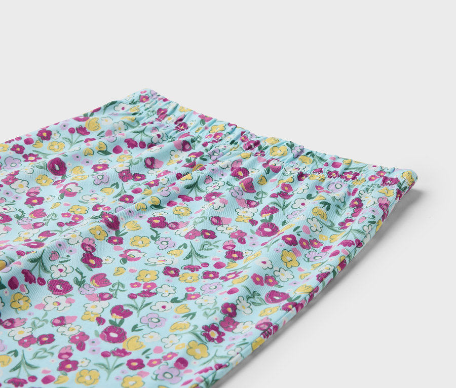 Détail d'un pantalon bleu clair avec un motif floral et une taille élastique.