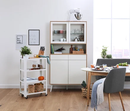 Intérieur de salle à manger avec un buffet, un chariot de service pour la cuisine et une chaise en tissu rembourrée.
