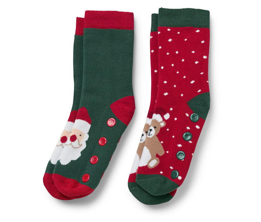 Deux paires de chaussettes de Noël. Une paire est verte avec une pointe rouge et une image du Père Noël, l'autre est rouge avec des points blancs et une image d'ours en peluche.