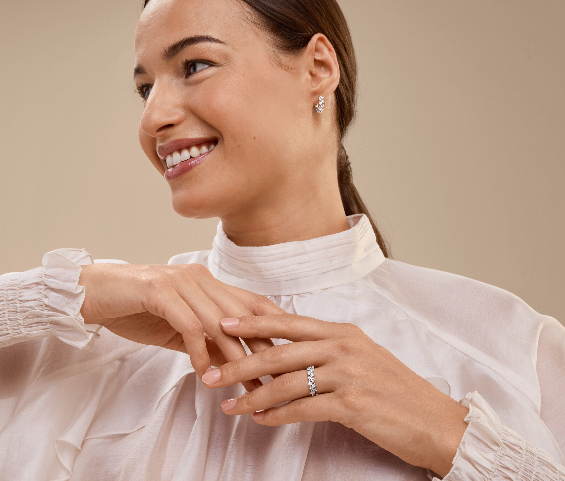 Femme souriante portant une bague et des boucles d'oreilles.