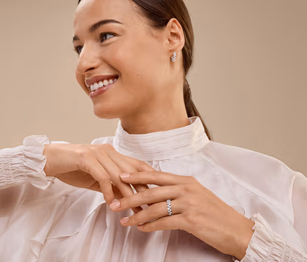 Femme souriante portant une bague et des boucles d'oreilles.