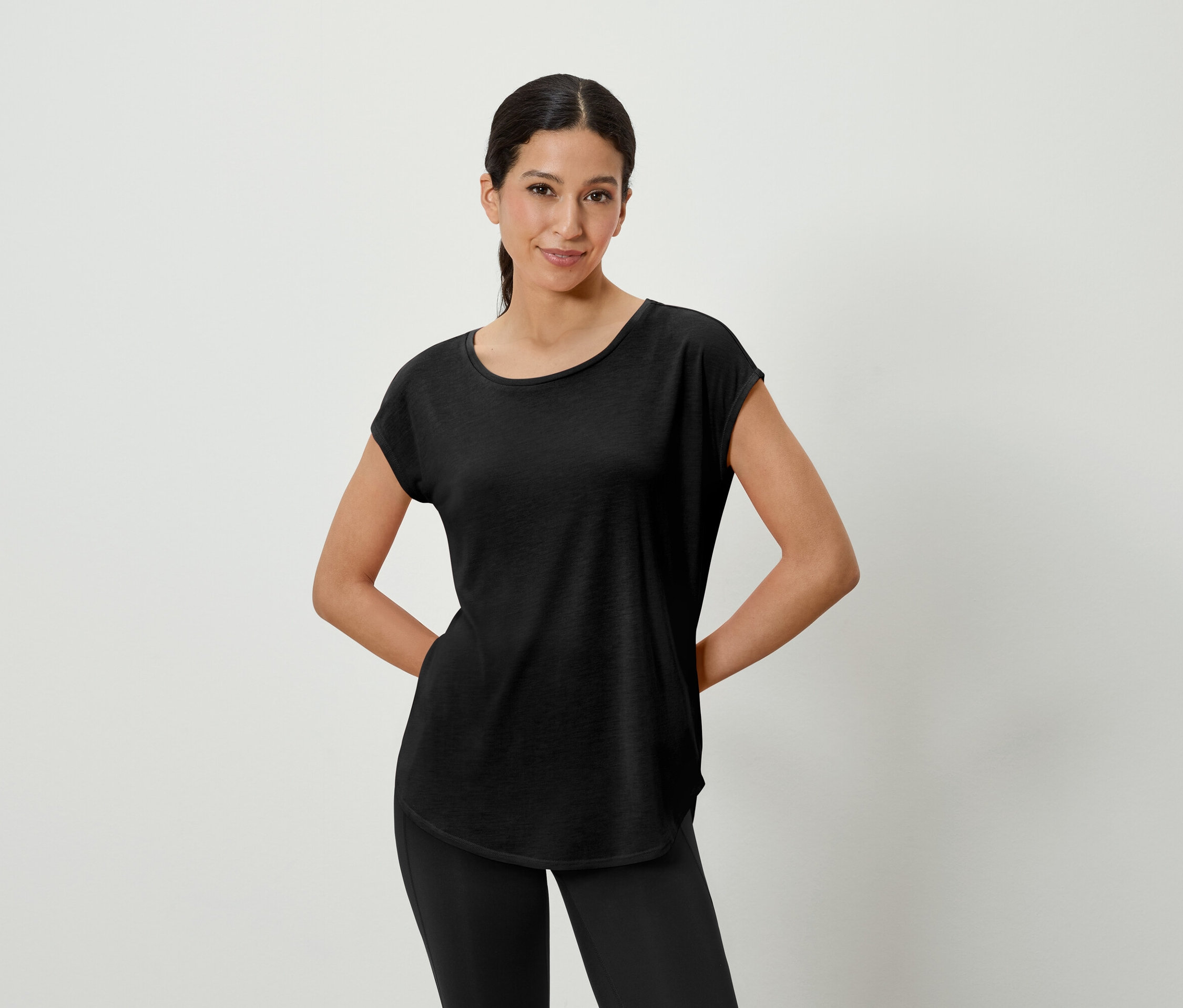 Femme posant en t-shirt noir et leggings.