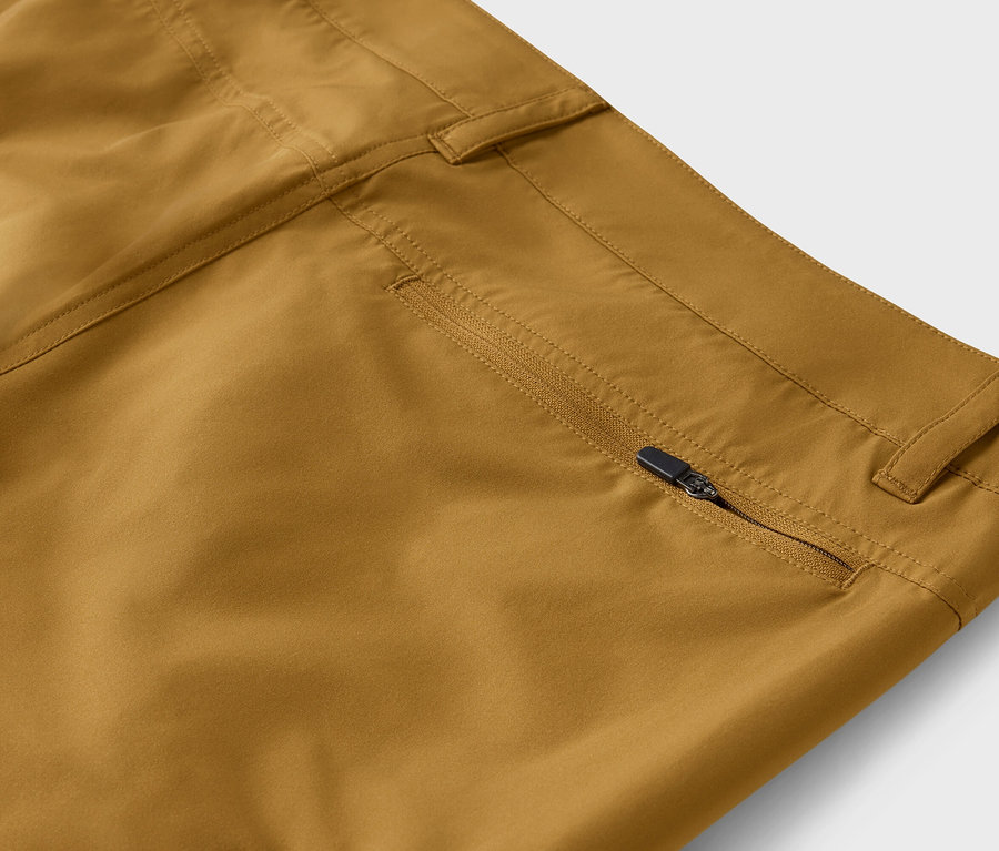 Gros plan d'un pantalon kaki avec une fermeture éclair partiellement ouverte sur la poche.