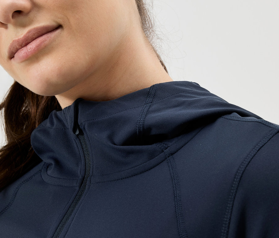 Gros plan d'une femme portant un sweat à capuche bleu marine zippé.