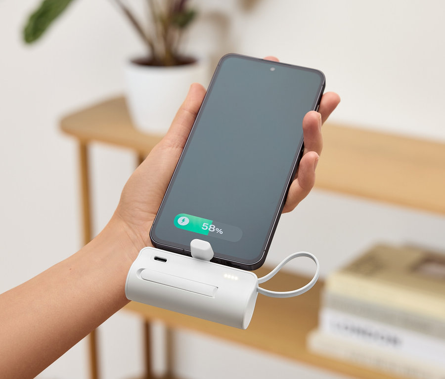 Une main tient un smartphone connecté à un chargeur portable blanc. Le niveau de la batterie du téléphone est de 58%.