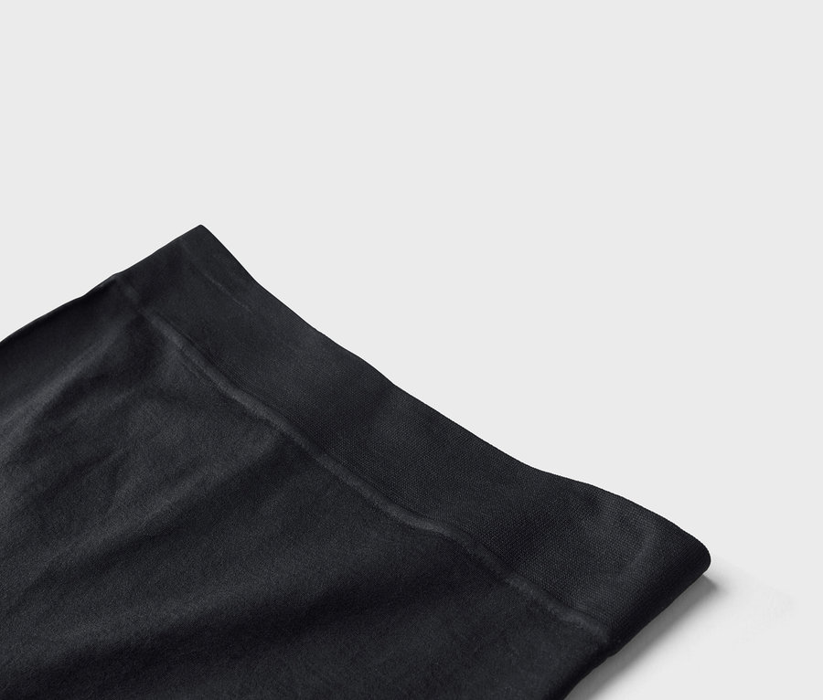 Gros plan sur un collant noir opaque avec une large ceinture sur fond blanc.