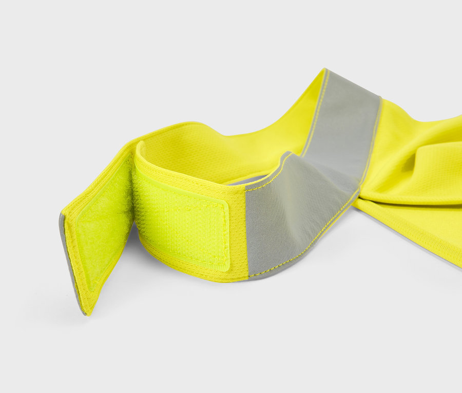 Gros plan d'une ceinture de sécurité jaune avec une bande réfléchissante et une fermeture velcro sur fond blanc.