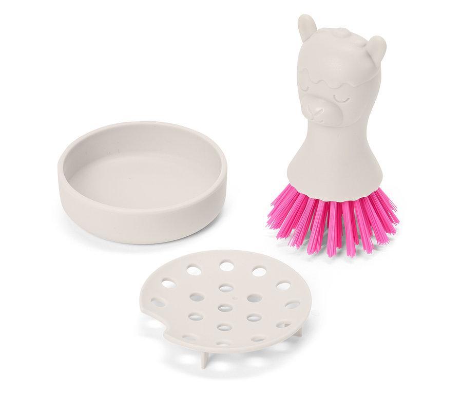 On voit un porte-brosse à vaisselle beige avec égouttoir et une brosse à vaisselle avec des poils roses et un manche en forme de lama.