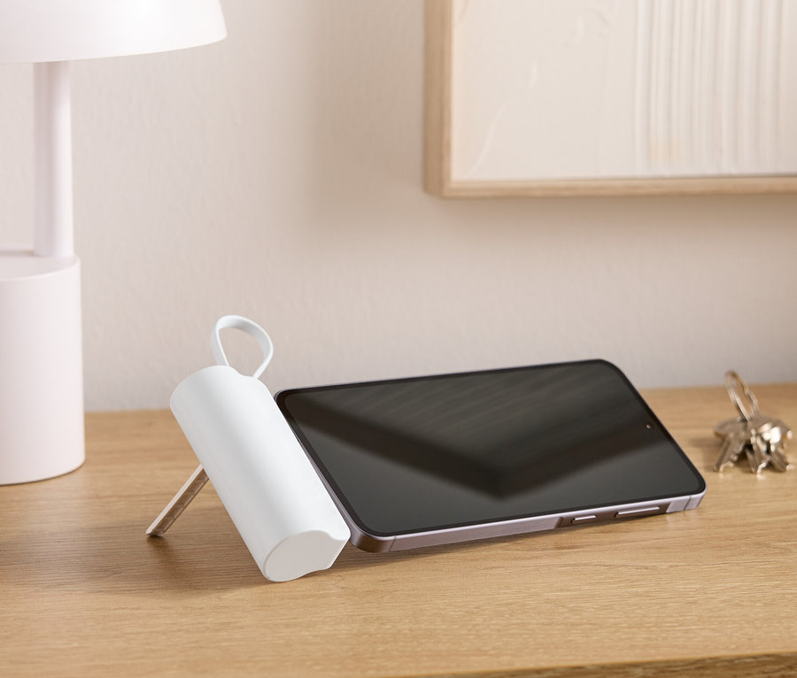 Sur une table en bois se trouvent une lampe, une tablette, un trousseau de clés et un objet blanc de forme cylindrique avec une poignée.