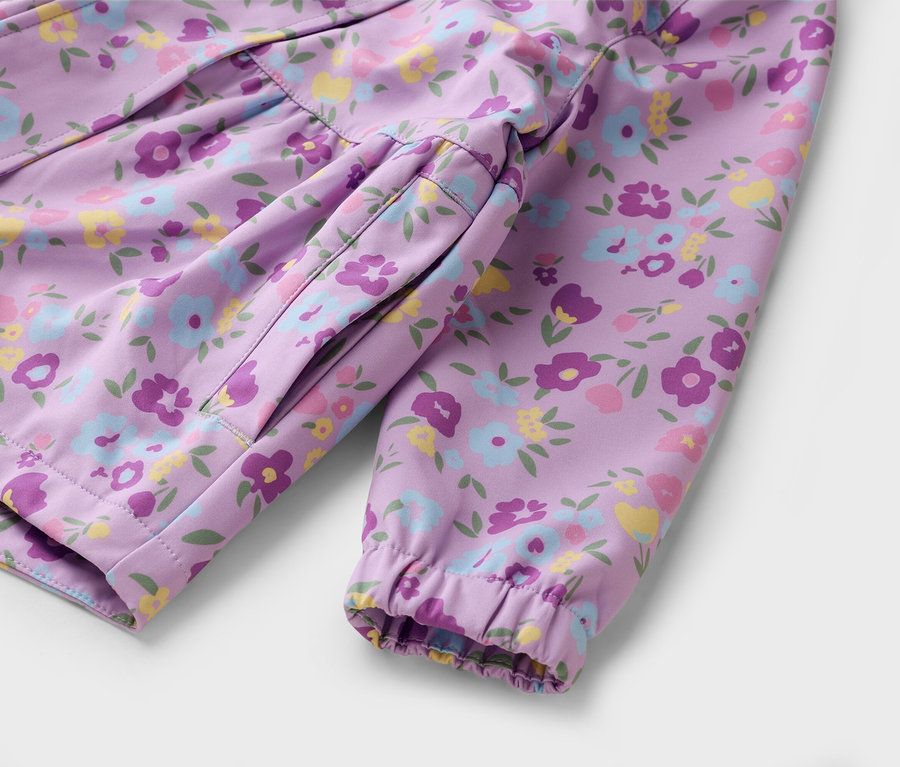 Gros plan d'une veste violette à motifs floraux posée sur une surface blanche.