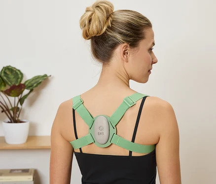 Femme portant un correcteur de posture vert sur un débardeur noir.
