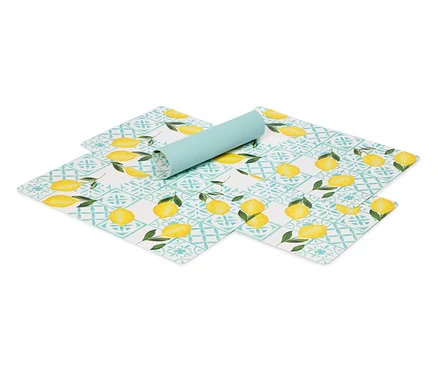 Sur un fond blanc, des sets de table à motif citron et un tapis bleu clair enroulé.