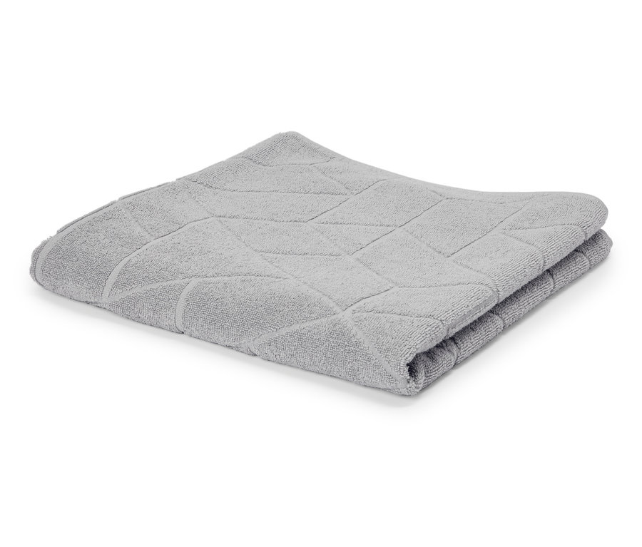 Une serviette gris clair pliée avec un motif géométrique est posée sur un fond blanc.