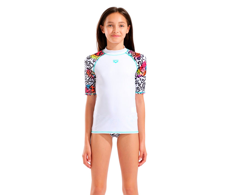 Une fille porte un rashguard Arena blanc avec des manches colorées et un maillot de bain à motifs.