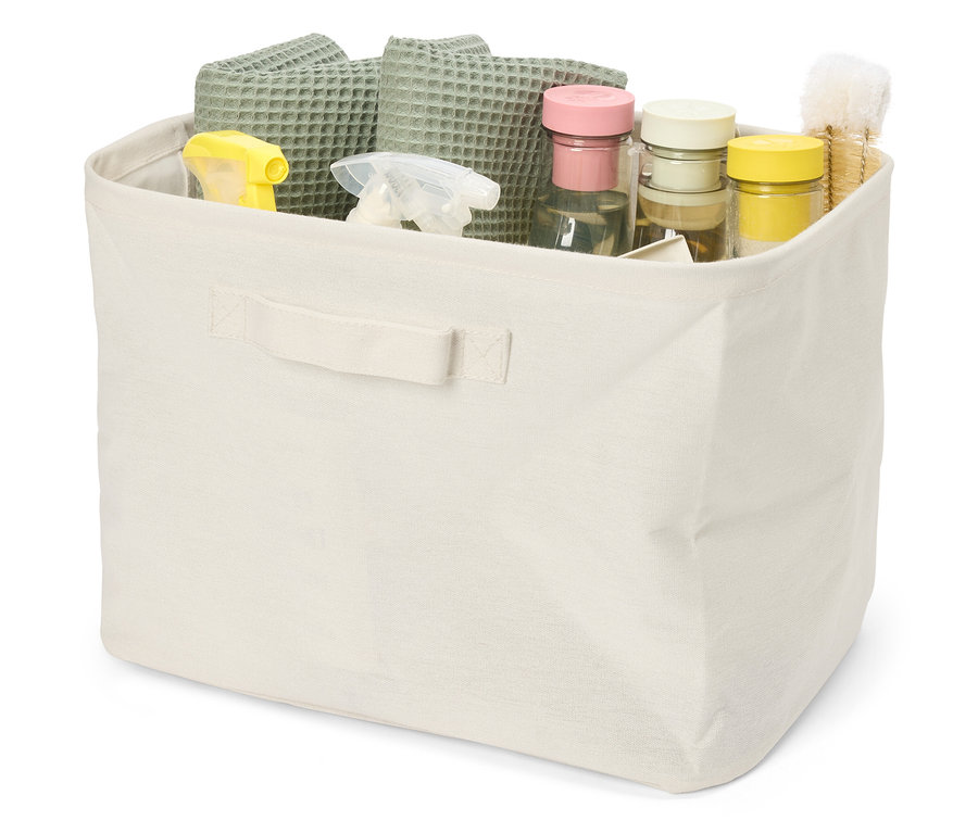 Un panier en tissu beige rempli de linges gaufrés verts, de vaporisateurs jaunes et transparents, et de bocaux de stockage.