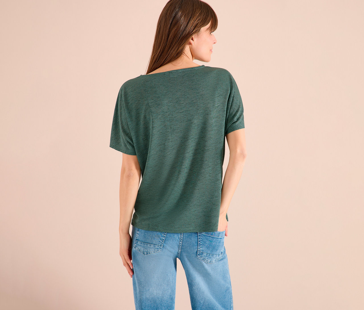 Vue de dos d'une femme aux cheveux bruns portant un t-shirt vert et un jean bleu.