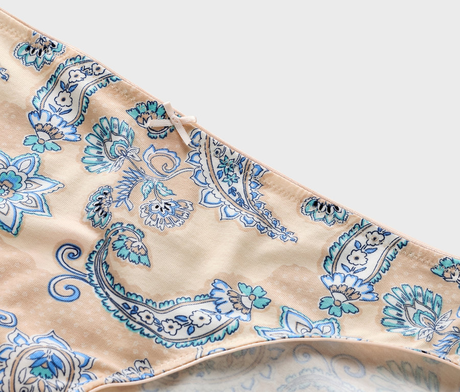 Gros plan d'une culotte beige avec un motif cachemire bleu et un nœud.
