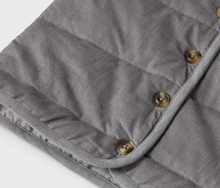 Gros plan d'un gilet en velours côtelé gris avec des boutons.