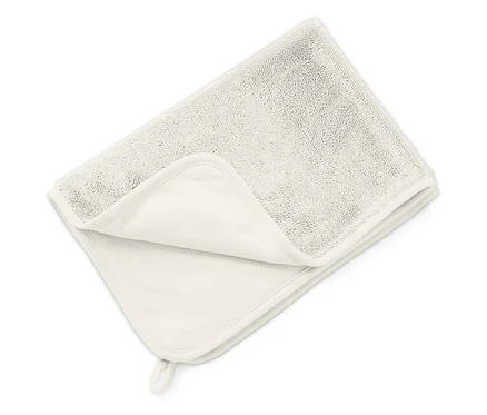 Une serviette claire pliée repose sur une surface blanche.