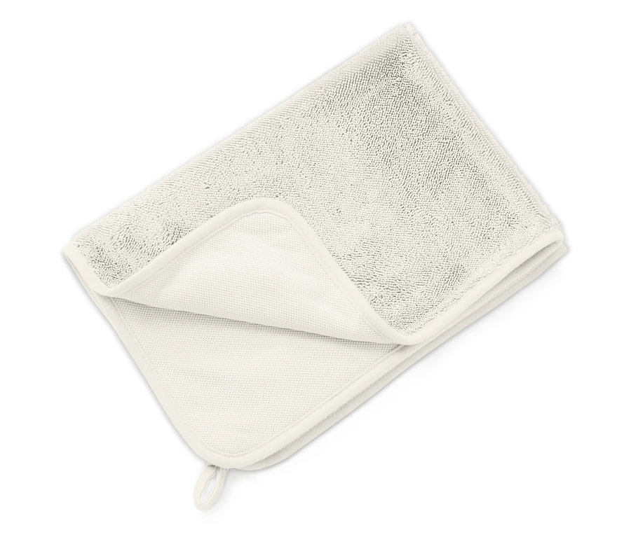 Une serviette claire pliée repose sur une surface blanche.