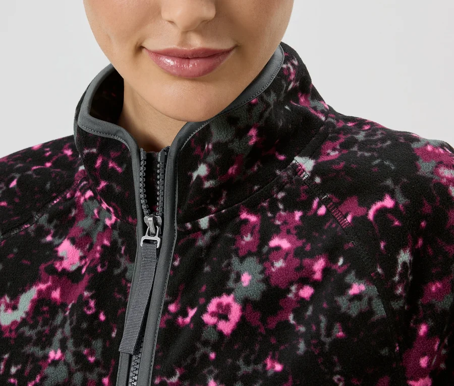 Gros plan d'une femme portant une veste polaire zippée à motif floral rose et gris.