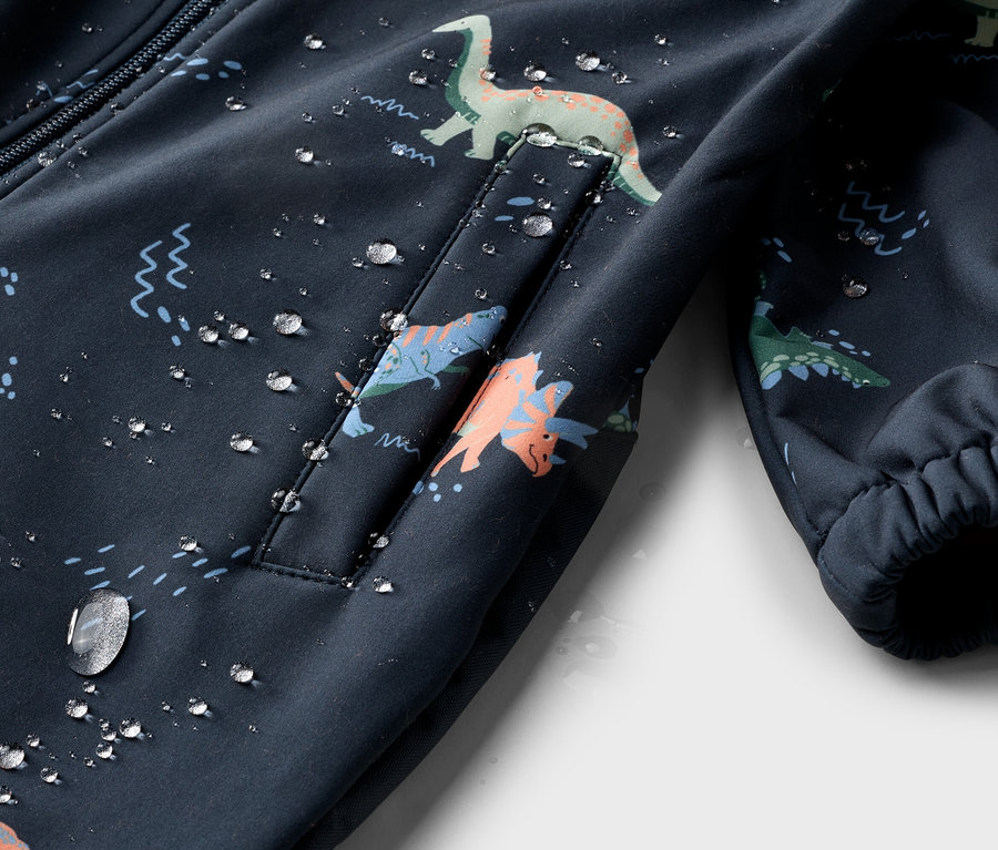 Gros plan sur une veste bleu marine avec motif dinosaure et gouttes d'eau.