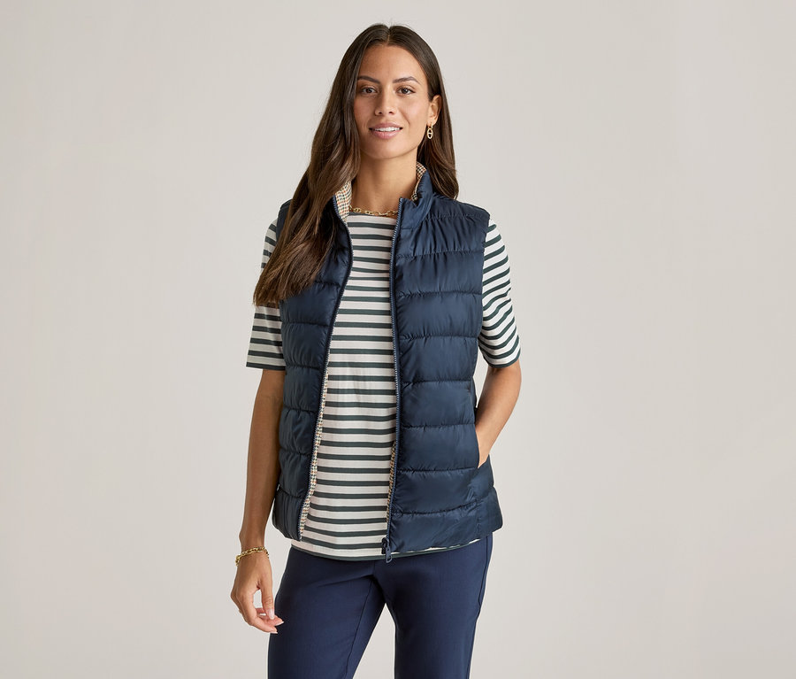 Femme portant un gilet bleu marine sur un t-shirt demi-manches vert à rayures.