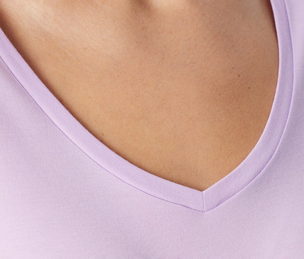 Cou et haut de la poitrine d'une personne portant un t-shirt violet clair à col en V.