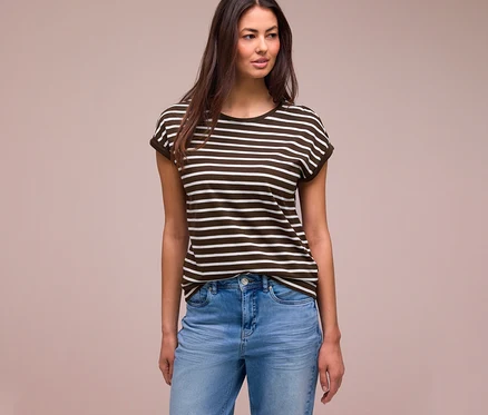 Femme aux longs cheveux foncés portant un t-shirt Street One rayé marron foncé et blanc et un jean bleu clair, regardant à droite.