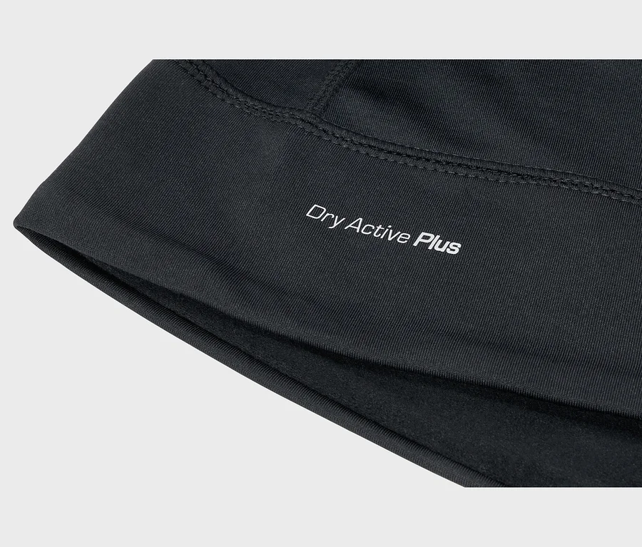 Gros plan sur un tissu noir avec l'inscription blanche « Dry Active Plus », des coutures visibles et une doublure intérieure douce.