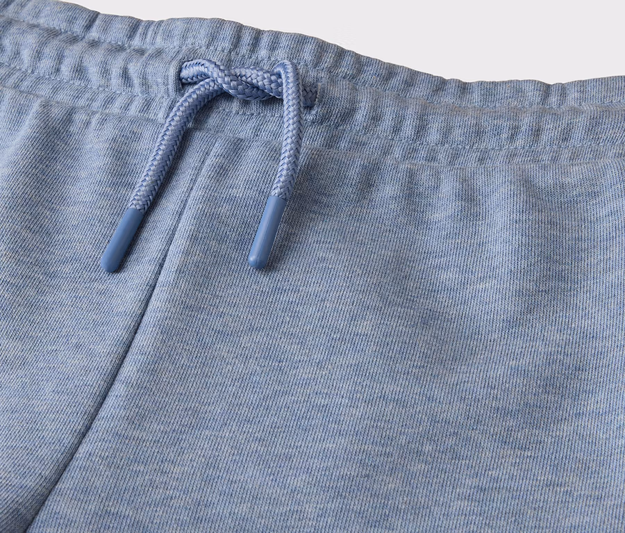 Gros plan d'un pantalon de jogging bleu clair avec une taille élastique et un cordon de serrage bleu avec des embouts bleus.