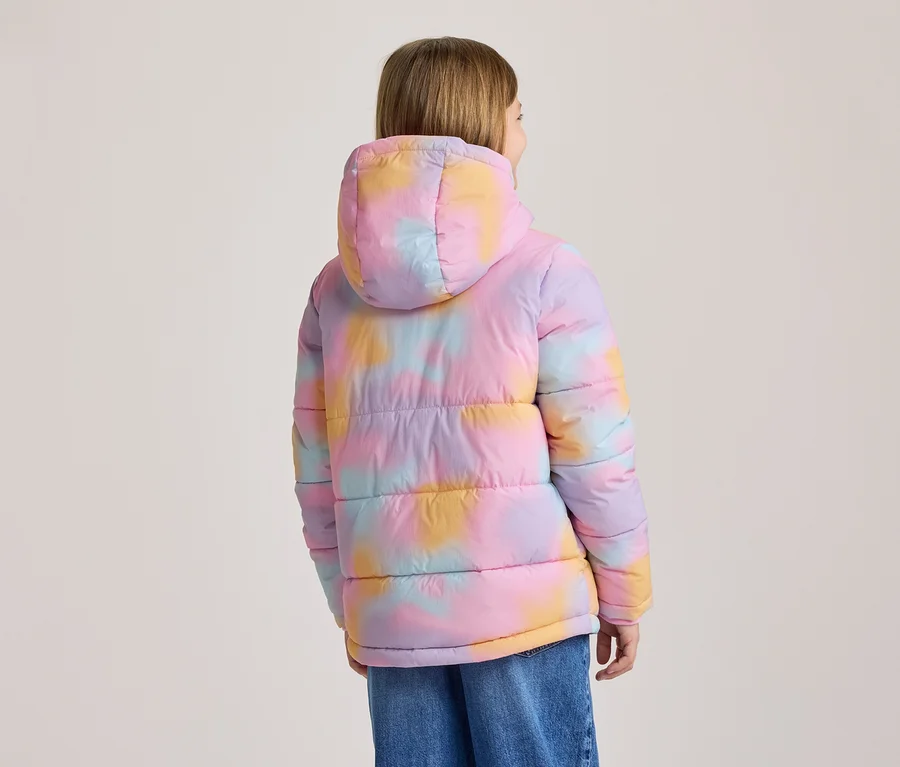 Personne de dos portant une doudoune colorée à capuche avec un motif tie-dye rose, violet, jaune et bleu, et un jean bleu.