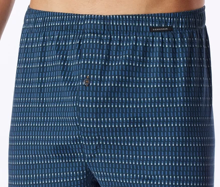 Caleçon pour homme bleu foncé avec une ceinture élastique et un motif de petits tirets bleus et blancs. Une fermeture boutonnée est visible, et le nom de la marque SCHIESSER est sur la ceinture.