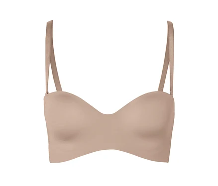 Un soutien-gorge couleur chair sans bretelles avec bretelles sur un fond blanc.