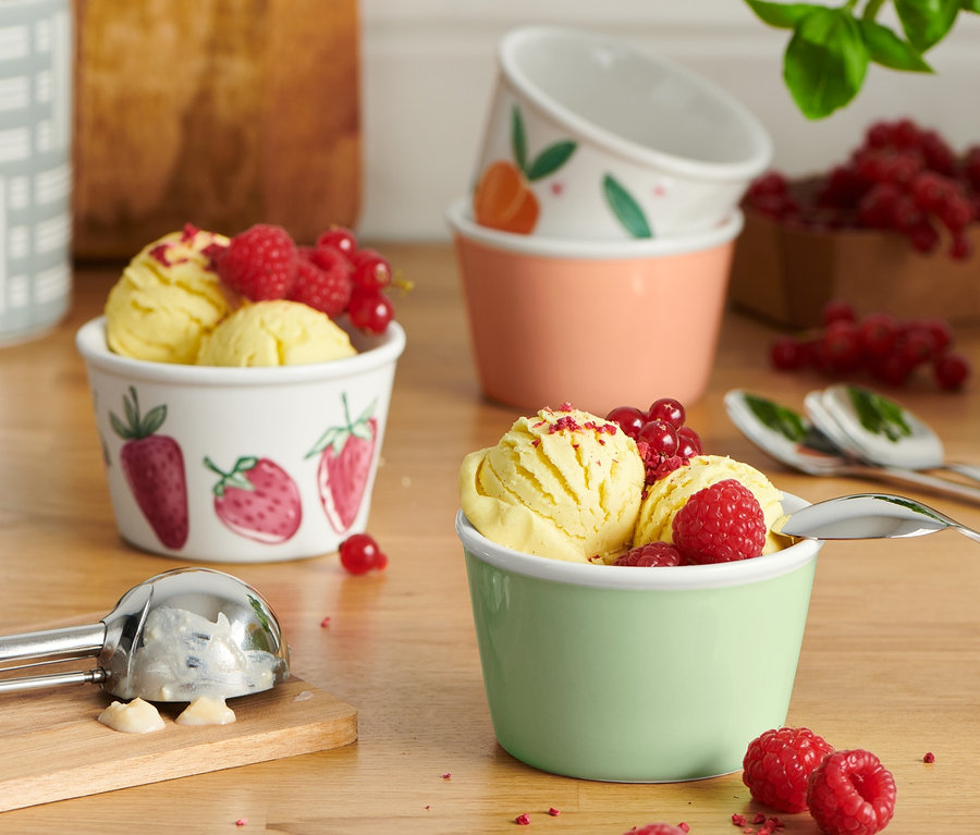 Glace jaune avec des framboises et des groseilles dans 4 coupes à glace.